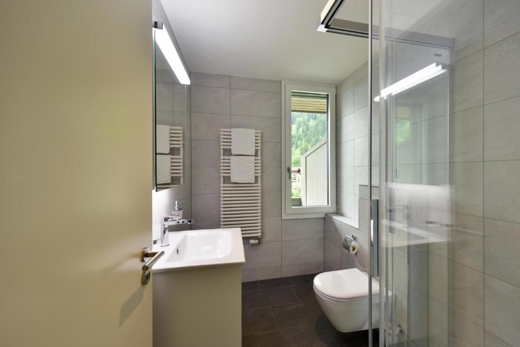 Ein modernes Badezimmer mit Duschkabine aus Glas, einem weißen Waschbecken und einer Toilette.