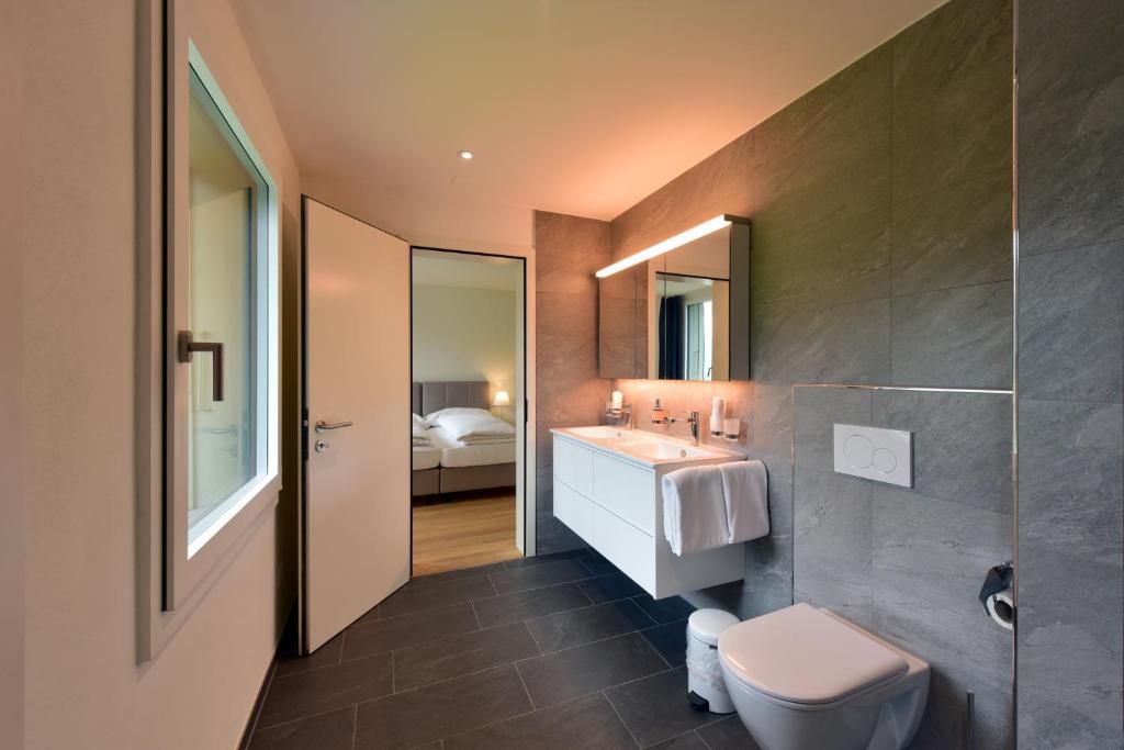 Une salle de bain moderne avec un grand miroir, un lavabo blanc et des toilettes.