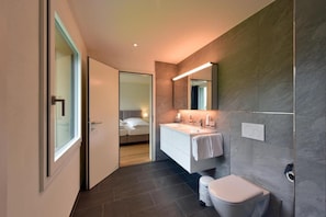 Une salle de bain moderne avec un grand miroir, un lavabo blanc et des toilettes.