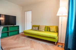 Un salon avec un canapé, un téléviseur à écran plat et une lampe.