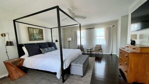 Una cama con dosel, un banco, un aparador de madera, un televisor y un cuadro en la pared.