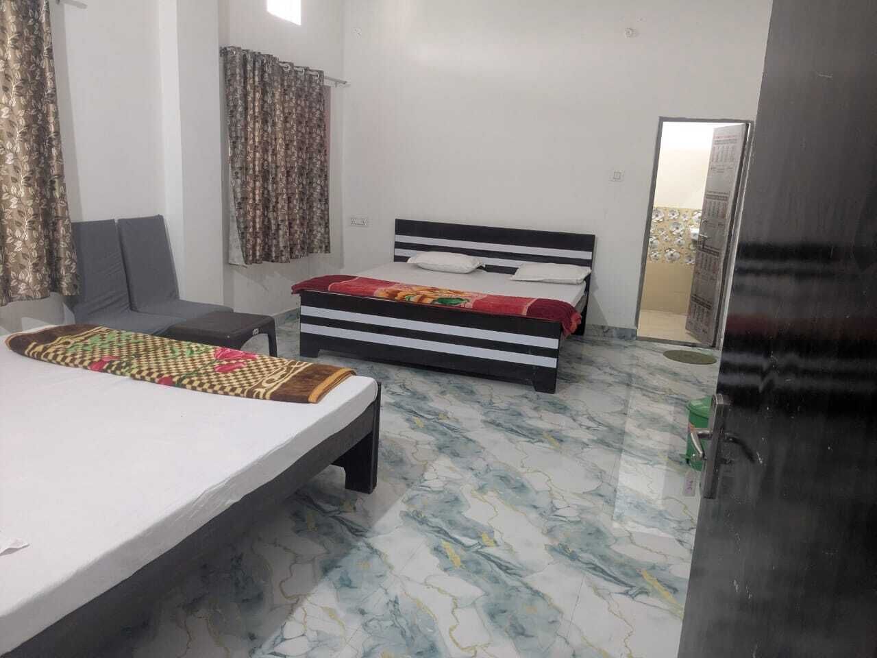 Quarto com duas camas, um sofá, uma mesinha e um espelho.