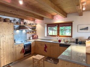 A kitchen with wooden cabinets, a stove, and a window with curtains.