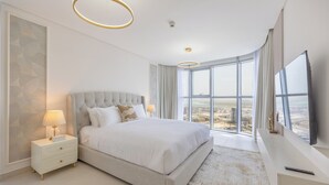 A bedroom with a large bed, bedside tables, a TV, and a view of the city. - Bloomfields 2BR plus Maid in Radiant  (Abu Dhabi)