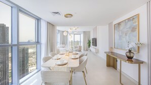 A modern dining area with a large table, chairs, and a view of the cityscape through large windows. - Bloomfields 2BR plus Maid in Radiant  (Abu Dhabi)