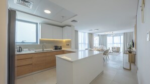 A modern kitchen with a central island, wooden cabinets, and a dining area with a white sofa and table. - Bloomfields 2BR plus Maid in Radiant  (Abu Dhabi)