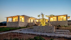 A modern building with a stone facade, large windows, and a well-lit interior. - ALAGNI CRETAN RESORT (Alagni)