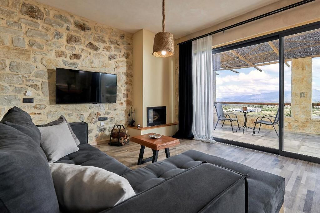 Una sala de estar con pared de piedra, televisor de pantalla plana, chimenea y un balcón con vistas.