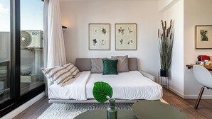Ein modernes Schlafzimmer mit einem großen Bett, Blick durch eine Glastür und Kunstwerken an den Wänden.