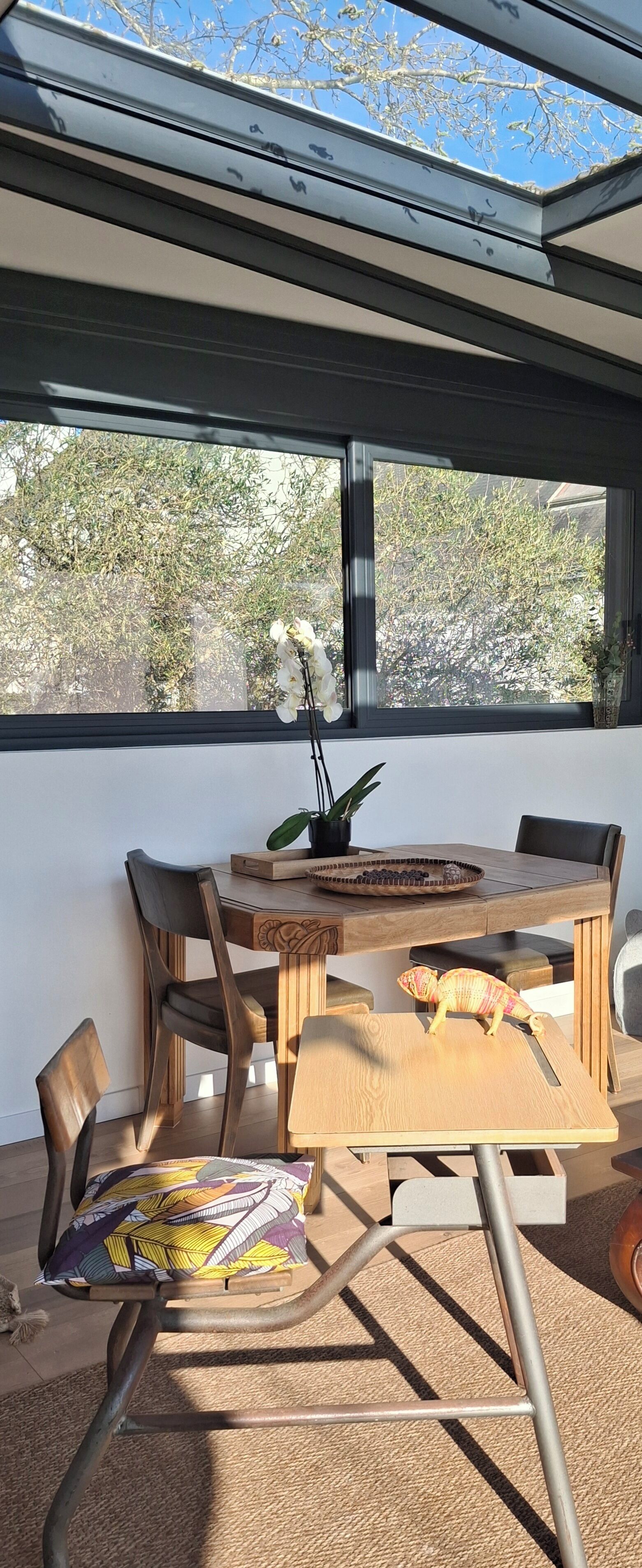 Un comedor con una mesa, sillas y vistas a través de un ventanal.