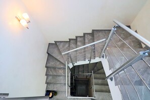 A staircase with a metal handrail, a light fixture on the wall, and a door at the bottom. - Modern Villa in a Quiet Location, 10' from the Center (Antibes)