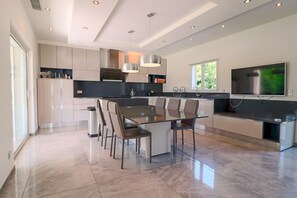 A modern kitchen with a central island, built-in appliances, and a large flat-screen TV. - Modern Villa in a Quiet Location, 10' from the Center (Antibes)