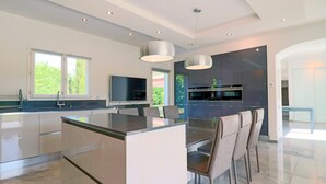 A modern kitchen with a central island, built-in appliances, and pendant lighting. - Modern Villa in a Quiet Location, 10' from the Center (Antibes)