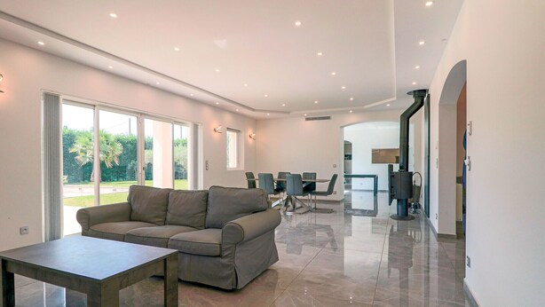 A modern living room with a sofa, a coffee table, and a dining area with chairs and a table. - Modern Villa in a Quiet Location, 10' from the Center (Antibes)