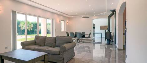A modern living room with a sofa, a coffee table, and a dining area with chairs and a table.