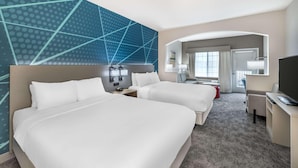 A hotel room with two beds, a desk with a TV, a chair, and a bathroom visible through an archway. - City Express by Marriott Redmond Airport (REDMOND)