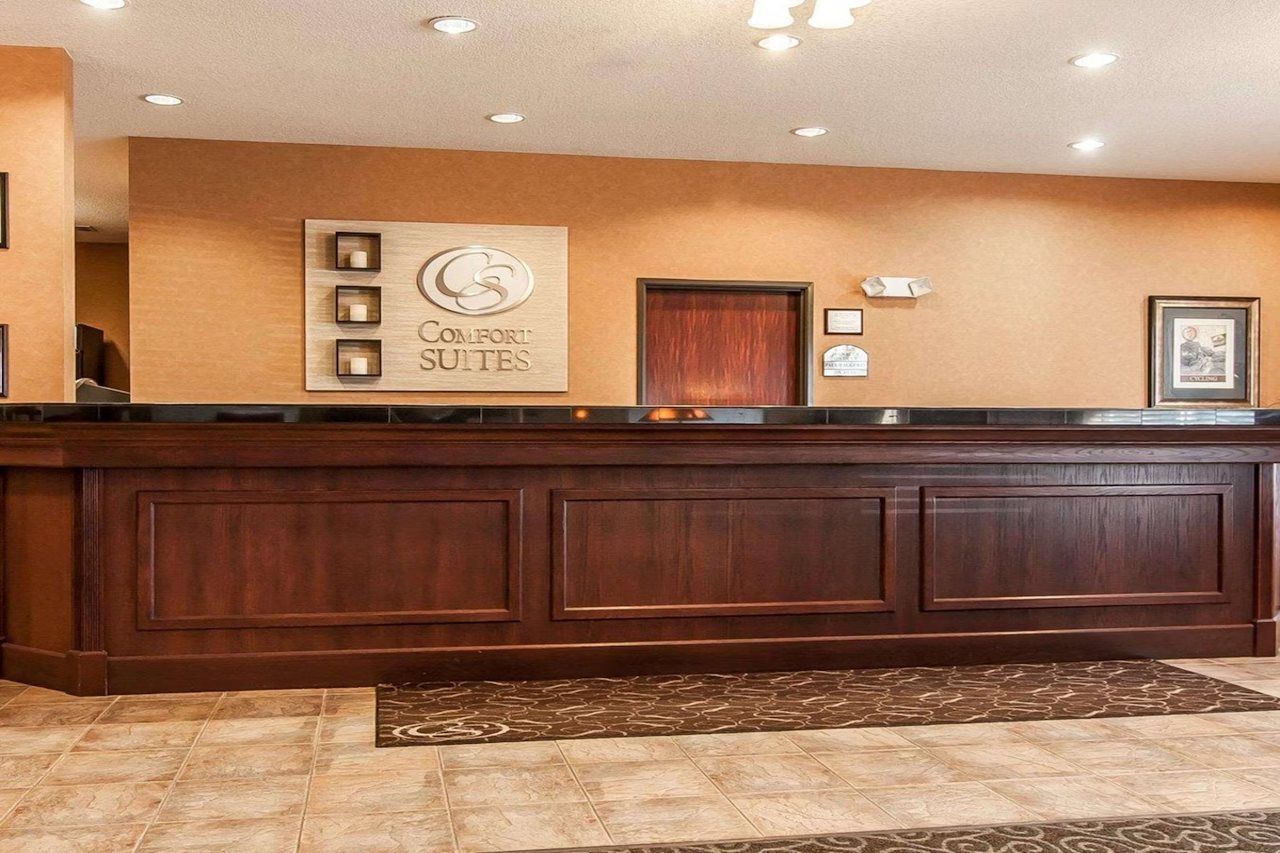 A reception desk with a wooden finish, a sign above it, and a framed picture on the wall.