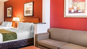 A hotel room with a bed, a sofa, a table, and two framed pictures on the wall. - City Express by Marriott Redmond Airport (REDMOND)