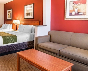 Una habitación de hotel con cama, sofá, mesa y dos cuadros en la pared.