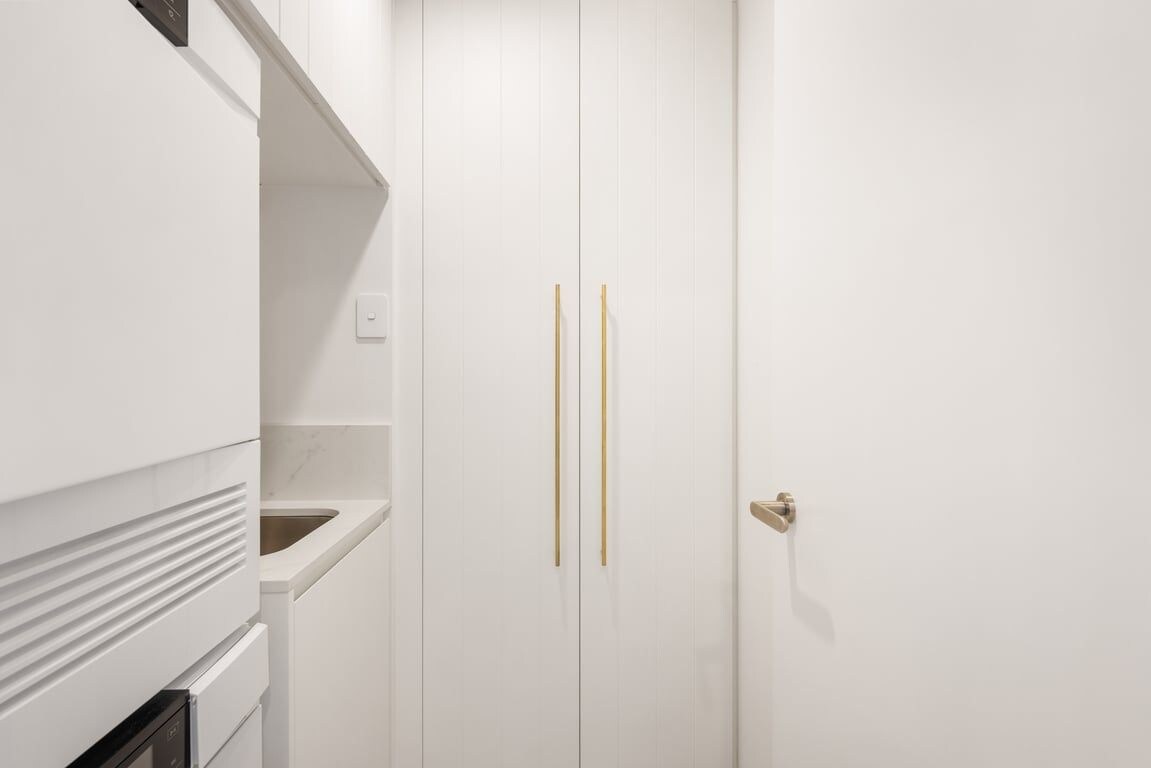 A white wardrobe with two golden handles and a door knob.