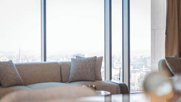 Una sala de estar moderna con un sofá, una mesa de centro y grandes ventanales con vista a la ciudad.
