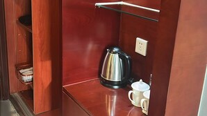 Une armoire en bois avec des étagères, une bouilloire et une tasse.