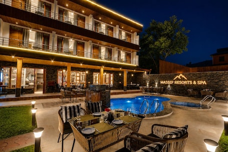 A multi-story hotel with outdoor seating, a pool, and a spa sign.
