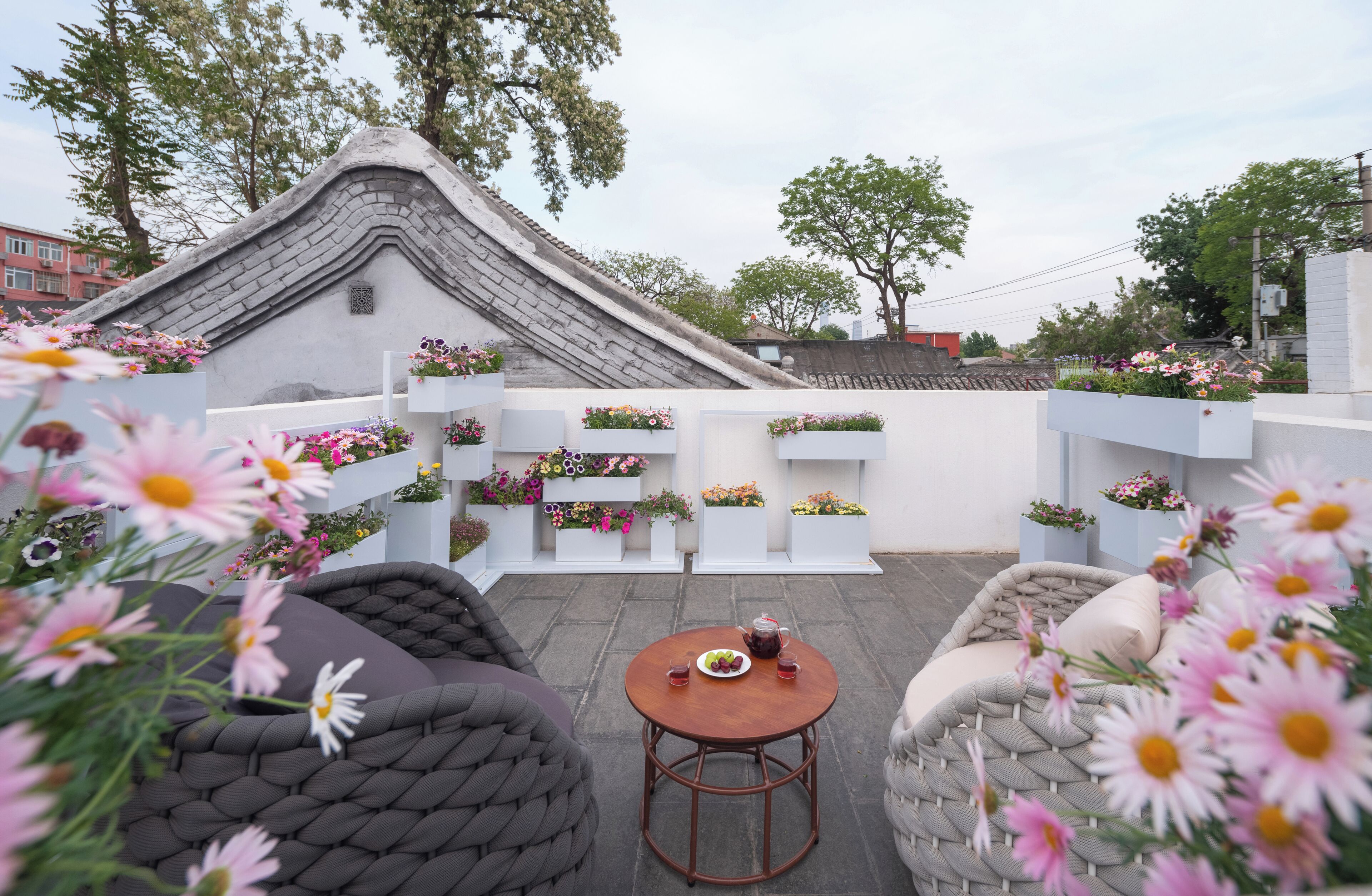 Une cour dotée d’une architecture traditionnelle, d’un espace extérieur aménagé pour s’asseoir et de jardinières fleuries.