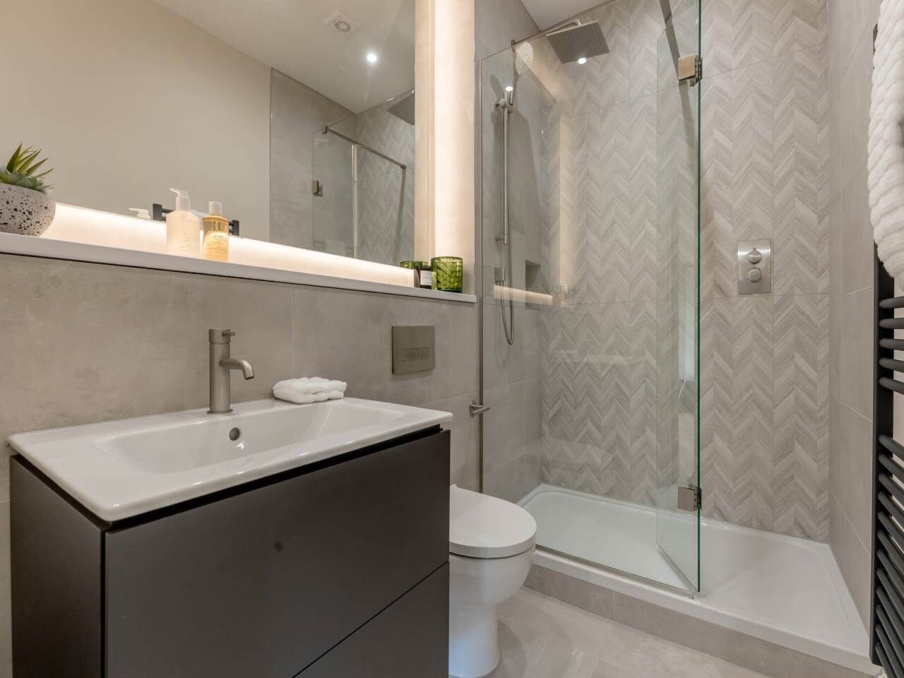 A modern bathroom with a glass shower enclosure, a white sink, and a toilet.