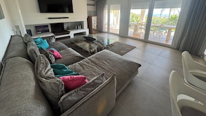 A modern living room with a large sofa, a flat-screen TV, and a glass coffee table. - Ibiza Serenity Estate (Can fornet)