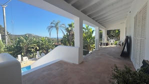 A covered outdoor area with a pool, white walls, and a view of palm trees and hills. - Ibiza Serenity Estate (Can fornet)