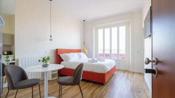 Ein Hotelzimmer mit einem Bett, einem kleinen Tisch, zwei Stühlen, einem Blumentopf und einem Fenster.
