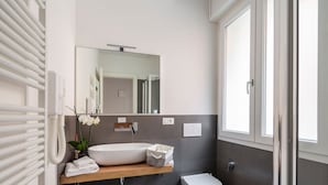 A modern bathroom with a white sink, a mirror, a toilet, and a radiator. - Strazzacappe Comfort Rooms by Wonderful Italy (Bologna)