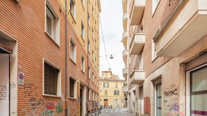 A narrow urban street with buildings on both sides, some with visible graffiti. - Strazzacappe Comfort Rooms by Wonderful Italy (Bologna)
