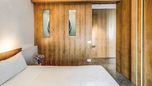 A hotel room with a wooden accent wall, a bed with white linens, and a vase with flowers. - Suite Priora with sea view (Priora)