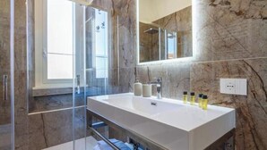 A modern bathroom with a large mirror, marble walls, and a glass shower enclosure. - Mercato Centrale | New Apartment (Milano)
