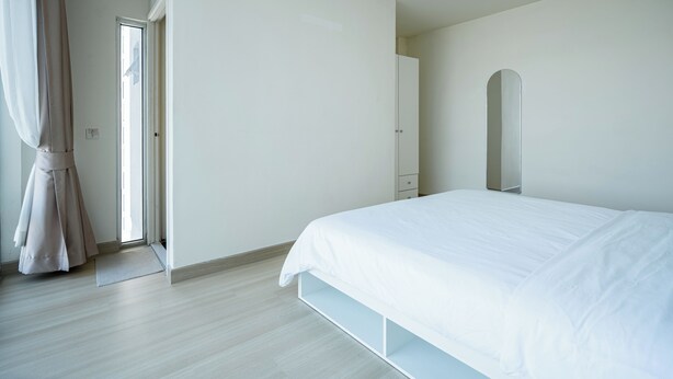 A bedroom with a bed, a door, and a mirror.