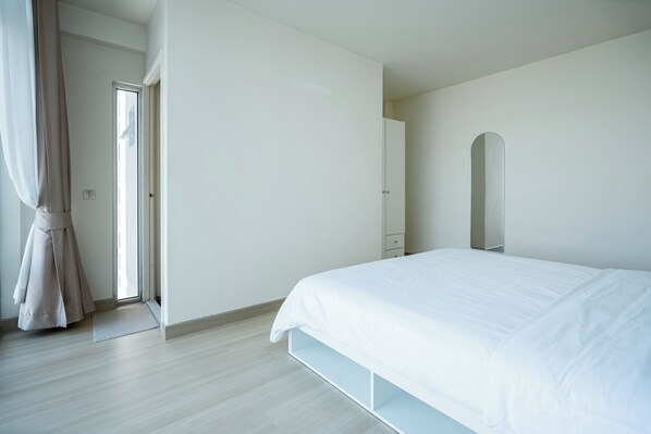 A bedroom with a bed, a door, and a mirror.