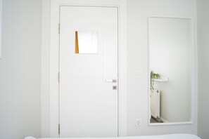 A white door with a small window, a mirror on the wall, and a radiator visible through the mirror. - Stylish 1-Bedroom Apartment Near Taksim Deniz Apartman (İstanbul)