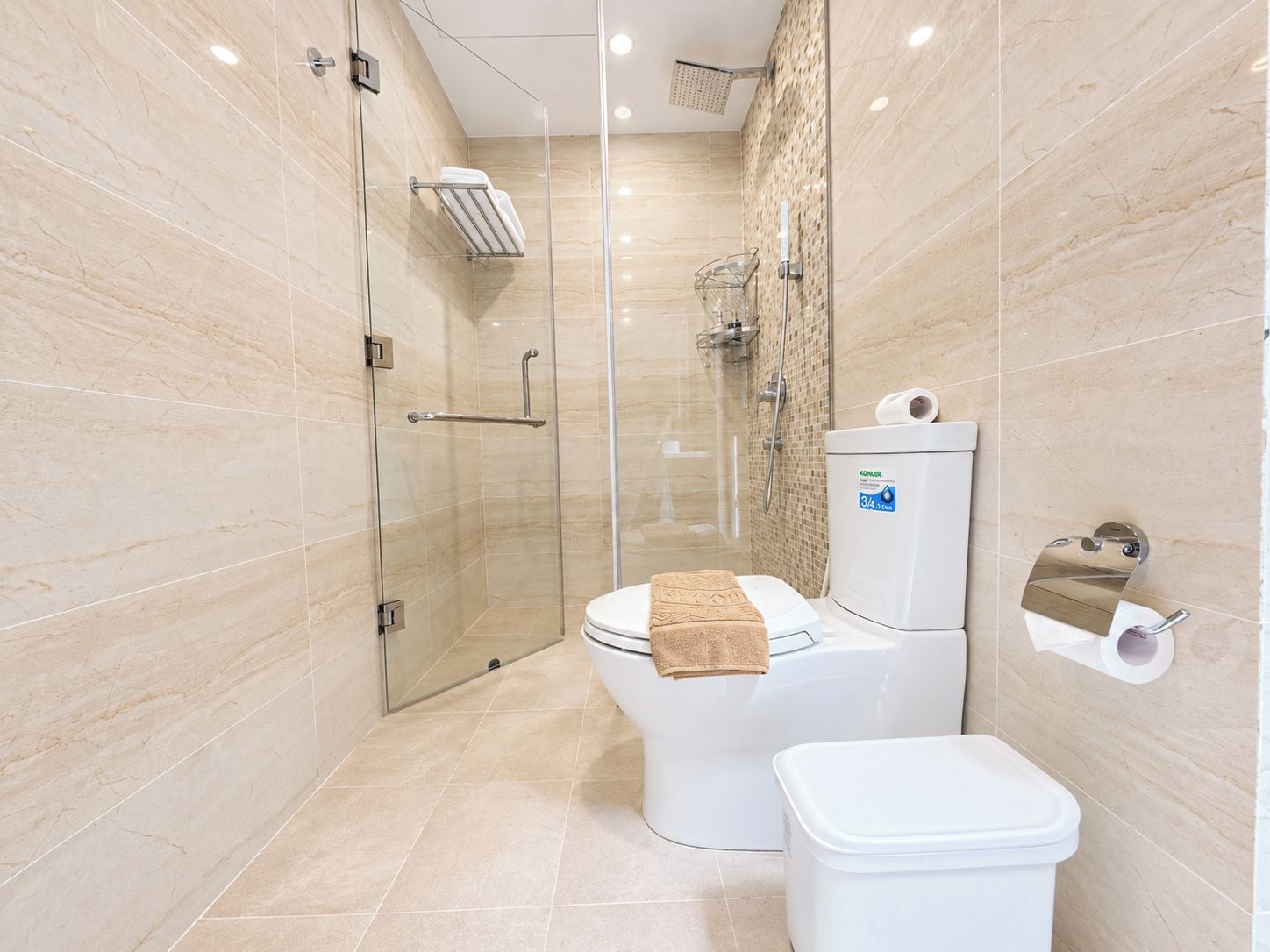 Un baño moderno con ducha de vidrio, inodoro con toalla y dispensador de papel higiénico.