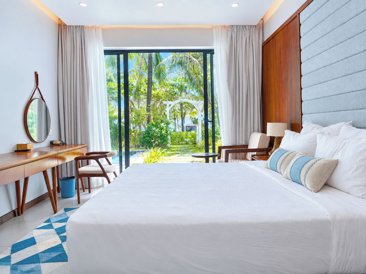 Ein Hotelzimmer mit einem großen Bett, einem Schreibtisch und Blick auf einen Garten.