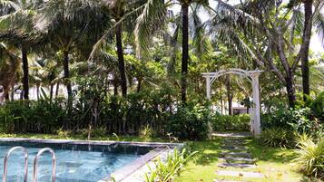 A swimming pool surrounded by lush greenery and a white pergola.