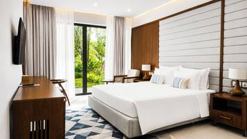 Habitación de hotel moderna con una cama grande, un escritorio, un televisor y vistas a zonas verdes.