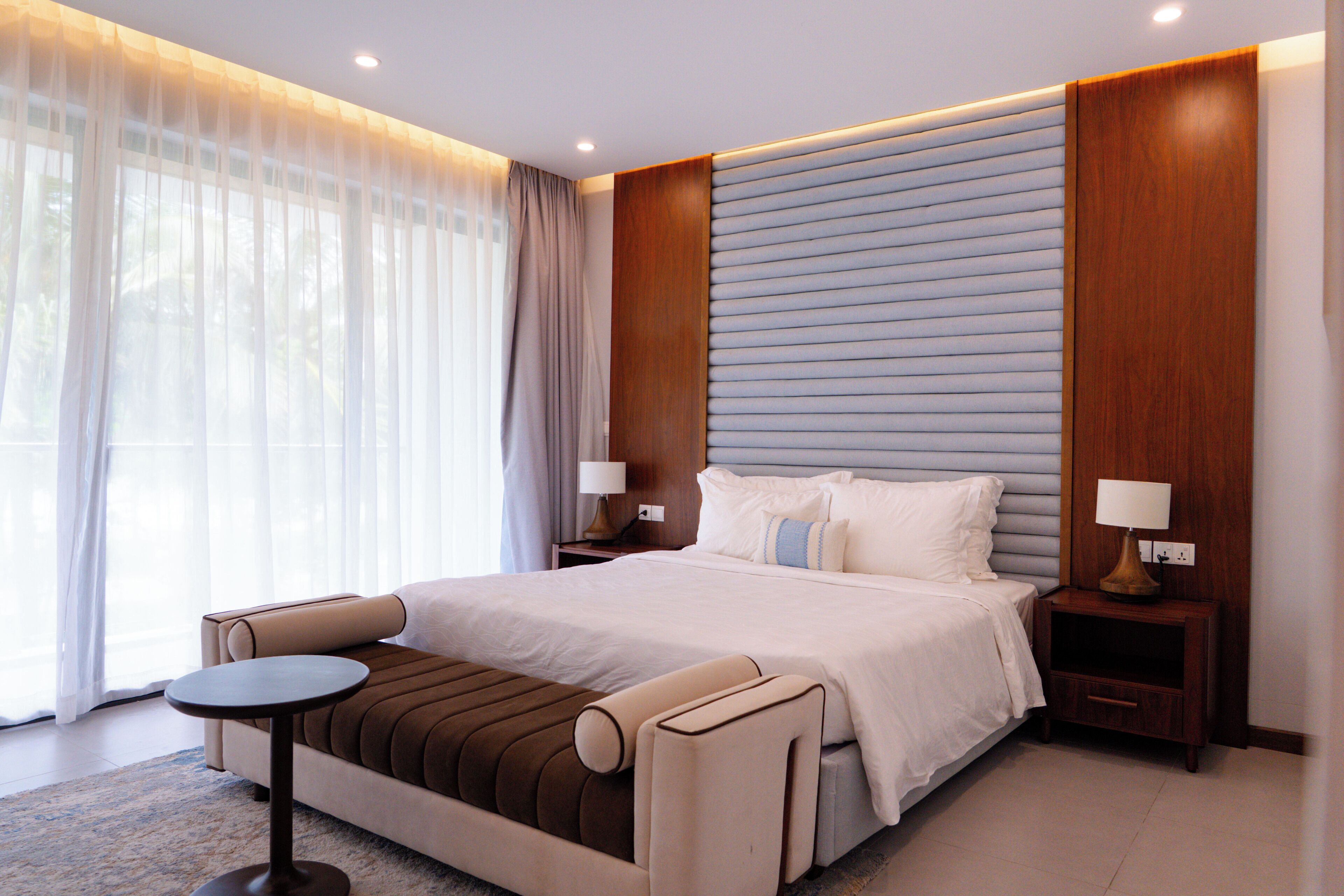 A modern hotel room with a large bed, a small round table, and a sofa.