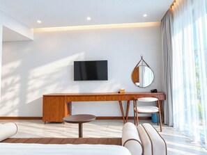 A modern hotel room with a flat-screen TV, a round mirror, a wooden desk, a round table, and a sofa. - Sonasea Villas Collection Long Beach Phu Quoc (Phu Quoc)