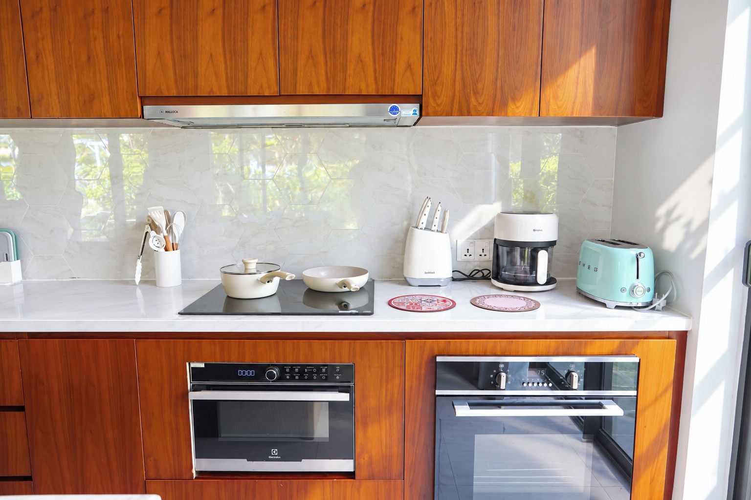 A modern kitchen with wooden cabinets, a built-in oven, a coffee maker, a toaster, and a stove.