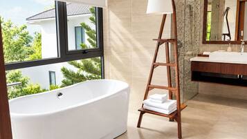 Un baño moderno con una bañera independiente, una escalera de madera con toallas, un ventanal grande y una zona de ducha con azulejos.