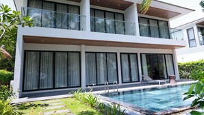 A modern two-story house with a swimming pool, large windows, and a balcony.