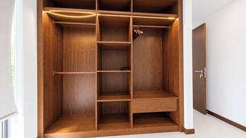 Un vestidor amplio con varias estanterías y espacio para colgar, una puerta con cerradura y suelo de baldosas.