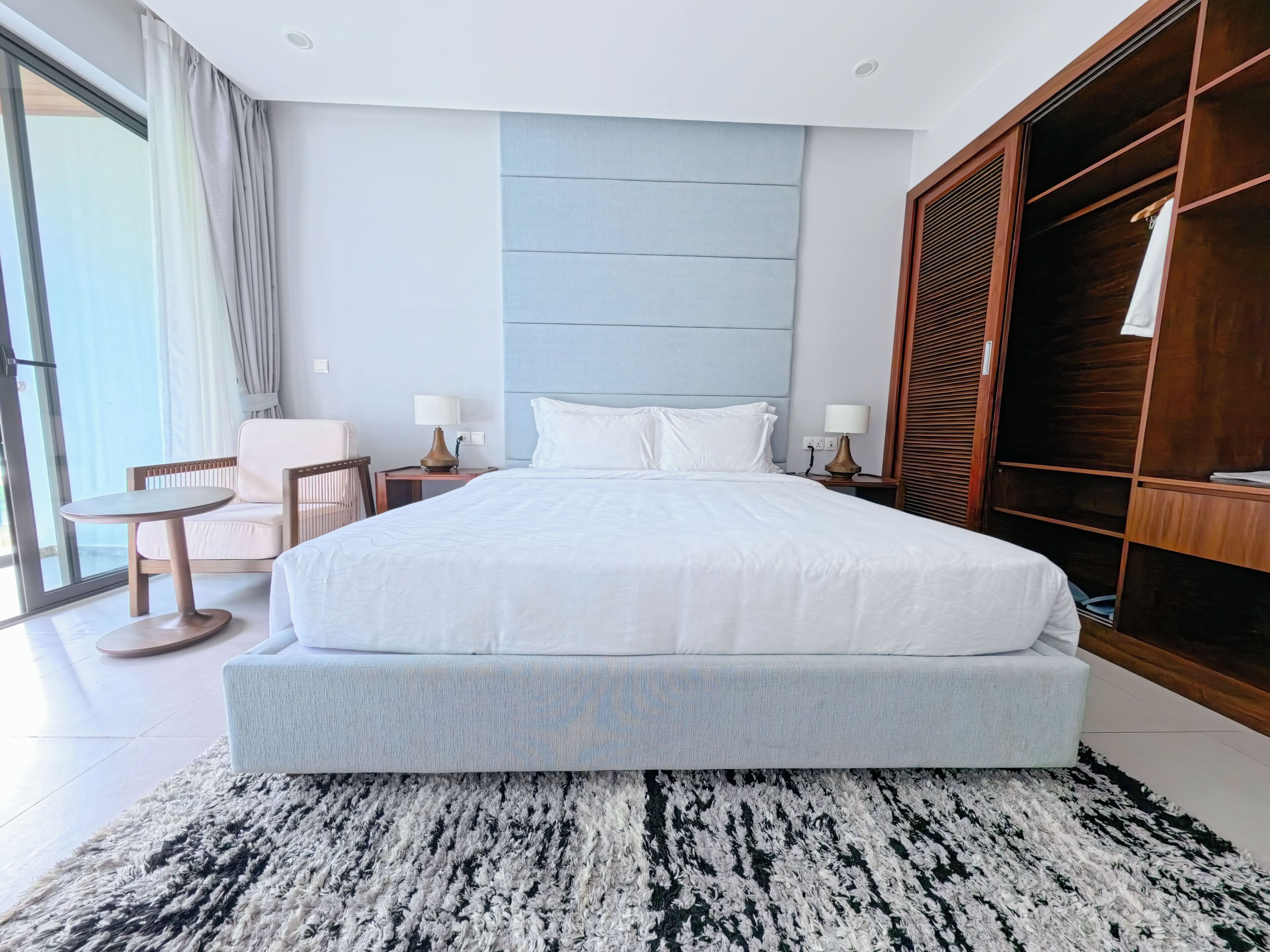 Una habitación de hotel moderna con una cama grande, una zona de estar con una mesa y un armario.